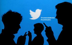 FILE PHOTO: People holding mobile phones are silhouetted against a backdrop projected with the Twitter logo in this illustration picture taken September 27, 2013. REUTERS/Kacper Pempel/Illustration